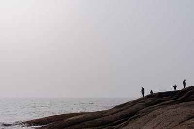 People on beach against clear sky