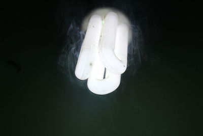 Close-up of illuminated light bulb over black background