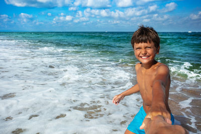 Rear view of shirtless boy standing at beach