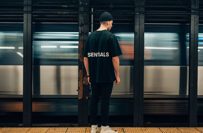 Rear view of man standing at railroad station