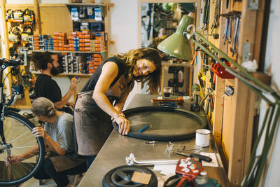 Male and female mechanics repairing bicycle in repair shop