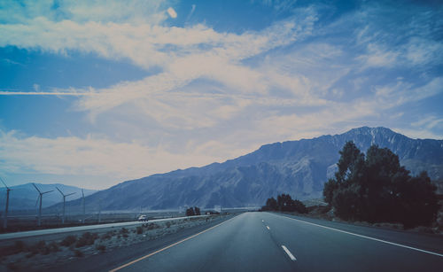 Road by mountains against sky