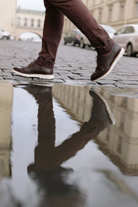 Handsome unrecognizable man in brown pants and dark leather shoes passing by camera. 