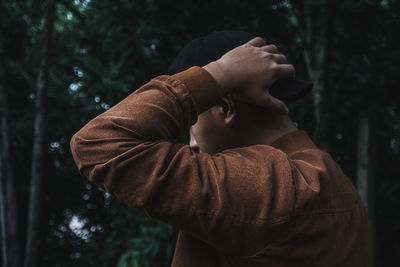 Close-up of young man standing against trees