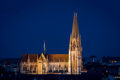 Illuminated building against blue sky at night