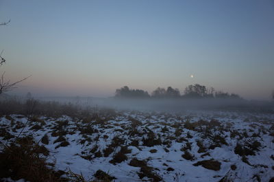 Snow covered field against sky during winter