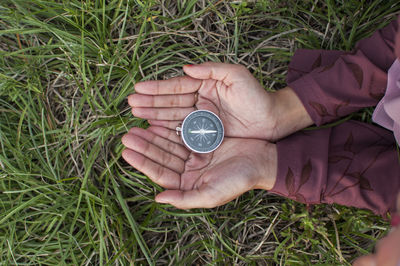 Close-up of woman holding navigational compass on field