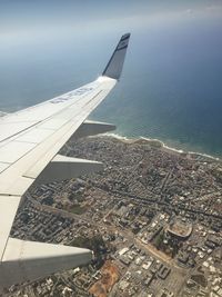 Aerial view of city by sea against sky