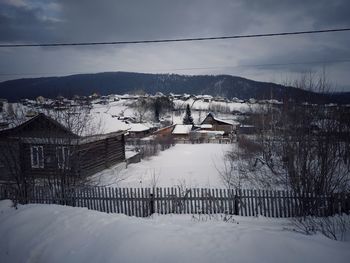 Houses on snow covered mountain against sky