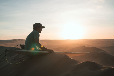 Man on shore against sky during sunset