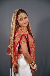 Portrait of smiling young bride standing against wall