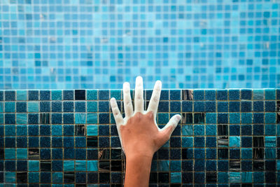 Close-up of hand against swimming pool