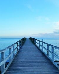 Pier over sea against clear blue sky