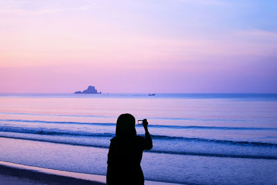 Silhouette man on beach against sky during sunset