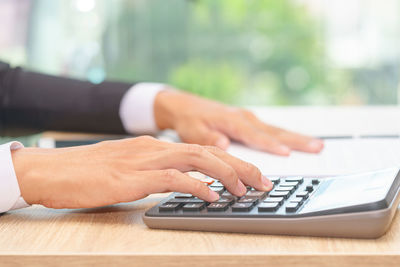 Midsection of person using mobile phone on table