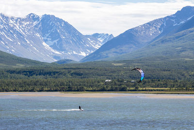 Kitesurfing in lake against mountain range