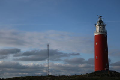 Low angle view of lighthouse by building against sky