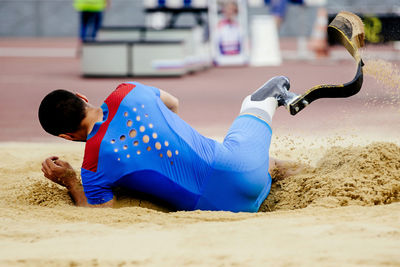 Low section of woman sitting on sand at beach