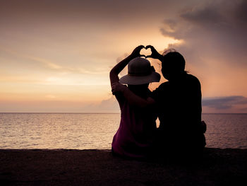 Couple on beach against sky during sunset