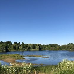 Scenic view of lake against clear blue sky