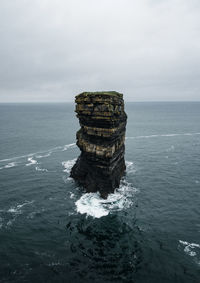 Stack of rock in sea against sky