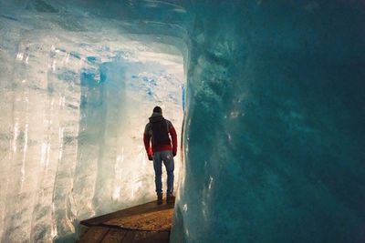 Rear view of man standing in ice cave