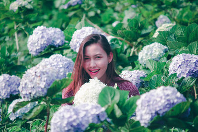 Portrait of smiling young woman against plants