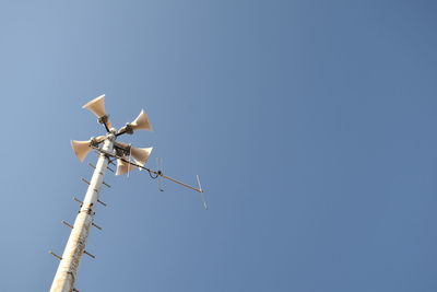 Low angle view of loud speakers against clear blue sky