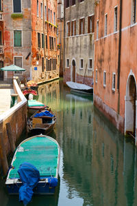 Boats in canal amidst buildings in city