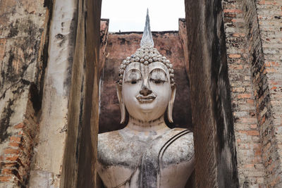 Buddha statue against wall of building