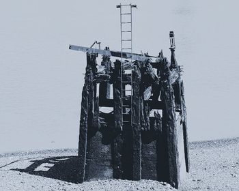 Abandoned building by sea against sky during winter