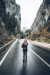 Rear view of woman standing on road against mountain range