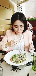 Young woman holding having food while sitting in restaurant