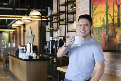 Handsome guy smiling while having a cup of coffee