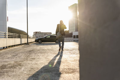 Mature man walking on parking level to his car, talking at the phone