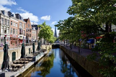 Canal amidst trees and buildings against sky