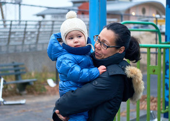 Mom carrying a toddler on the playground