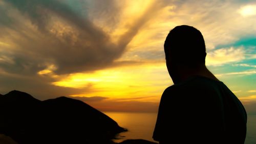 Silhouette of man looking at sunset