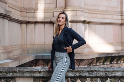 Portrait of woman standing against building