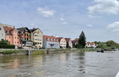 Buildings by river in town against sky