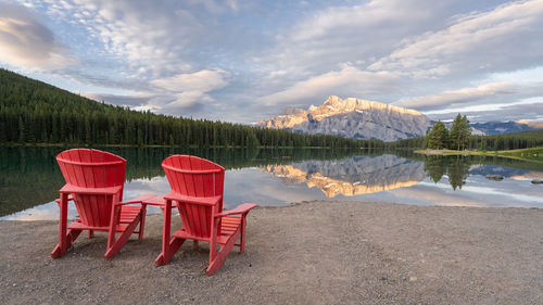 Chairs by lake against sky