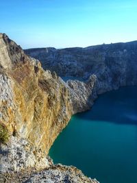 High angle view of rocks by sea against blue sky