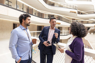 Smiling businessman planning strategy with colleagues in office corridor