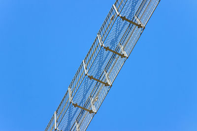 Low angle view of crane against clear blue sky