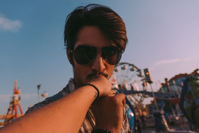 Portrait of young man wearing sunglasses against sky