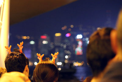 Cropped image of people wearing reindeer headbands at night during christmas