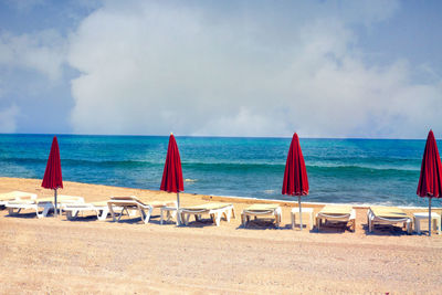 Deck chairs on beach against sky