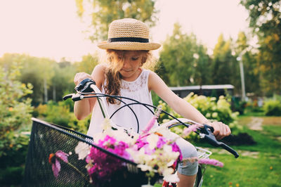 Smiling girl riding bicycle against trees