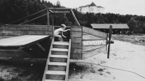 Boy sitting on boat against sky