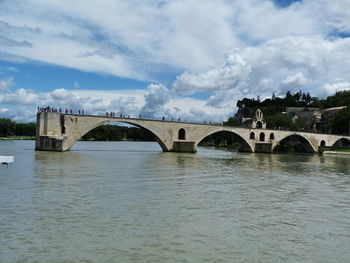 Arch bridge over river against cloudy sky